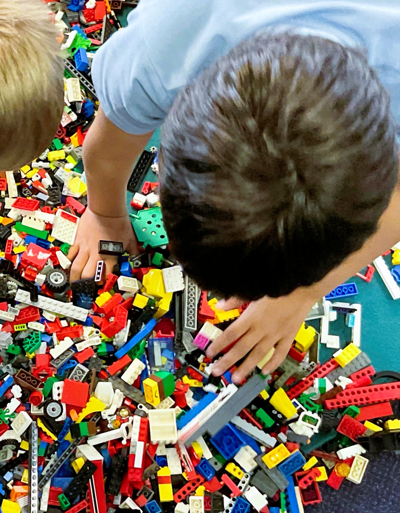 Boy with dark hair sifting through a pile of lego pieces on the floor