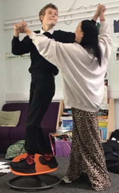 Student and staff member holding hands balancing