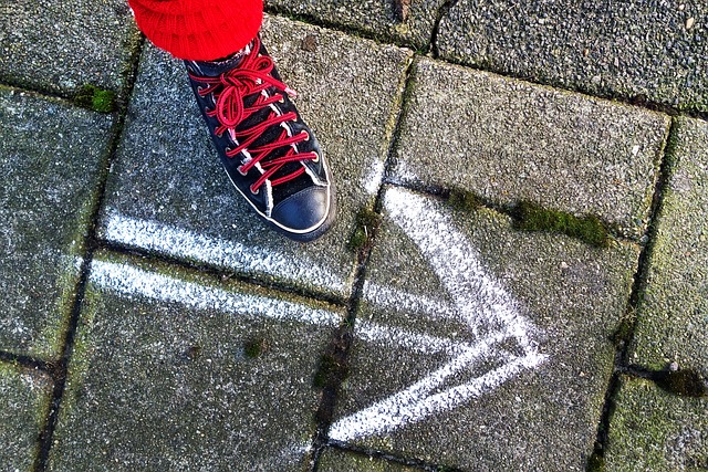 Foot on the pavement in front of a chalk forwards arrow